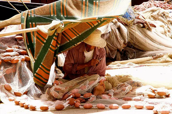 Tunezja | Mężczyzna naprawiający sieci rybackie Tunezja | Mężczyzna naprawiający sieci rybackie